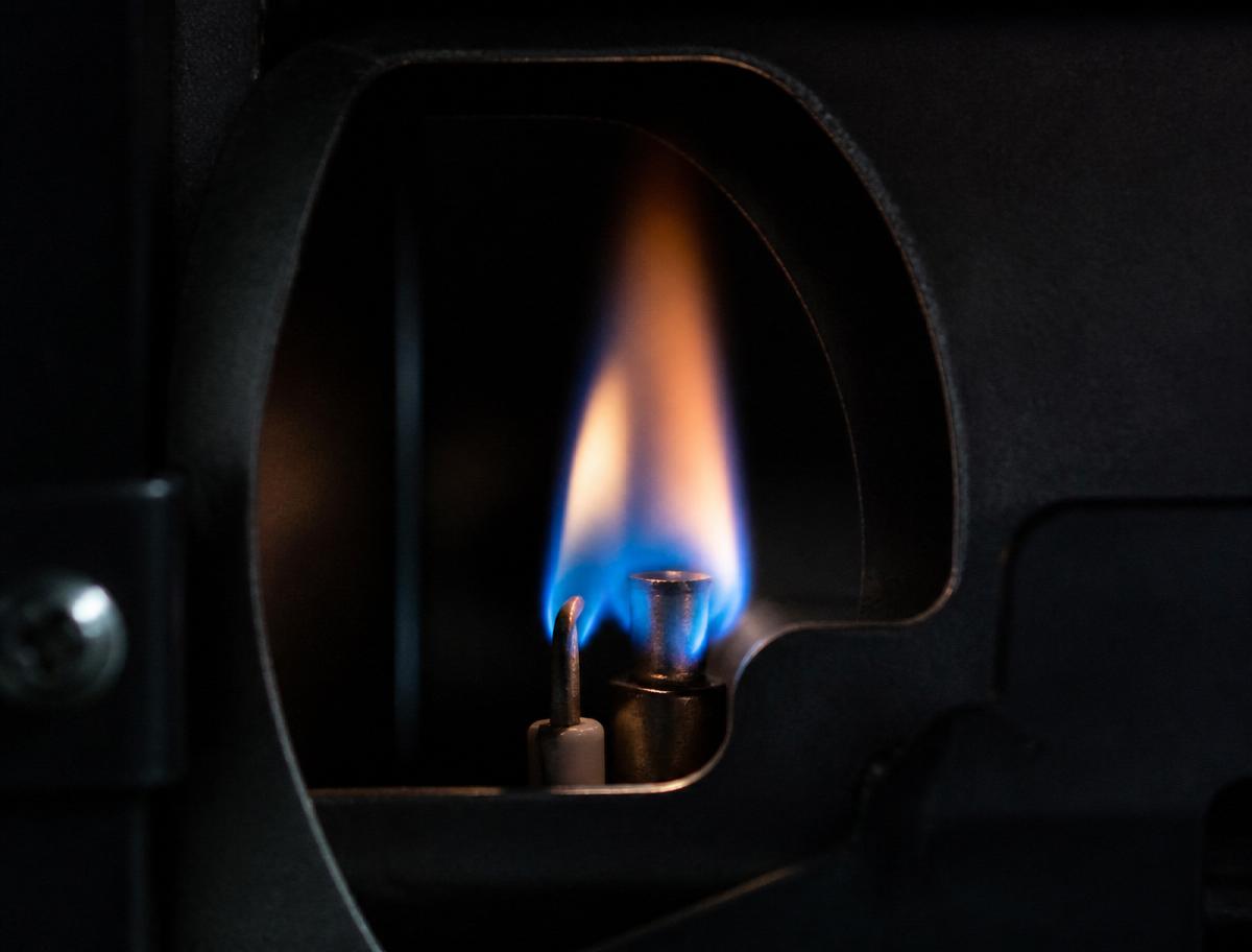 Blue pilot flame burning inside a high-efficiency furnace burner